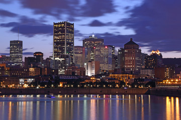 Montreal Downtown Panorama at sunset. Montreal reflected on the river at dusk with city lights and urban buildings. Montreal over river at sunset with city lights. Montreal reflected in water.