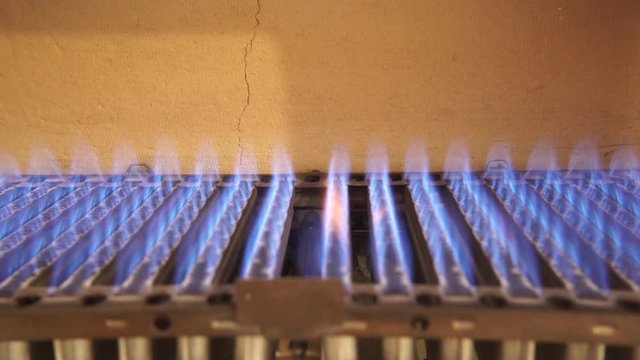 Heating at home. Blue flames of gas burner being burning, closeup detail inside of boiler furnace. 4K ProRes HQ codec