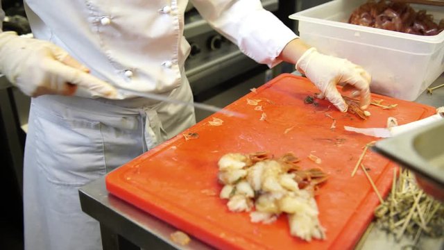 A female cook cleaning shrimps and preparing shrimp skewers, 4K