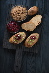 Obraz na płótnie Canvas Black wooden serving board with chicken liver pate sandwiches and cranberry sauce, high angle view