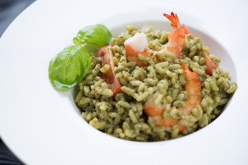Close-up of risotto with spinach, tiger shrimps and tomatoes, selective focus