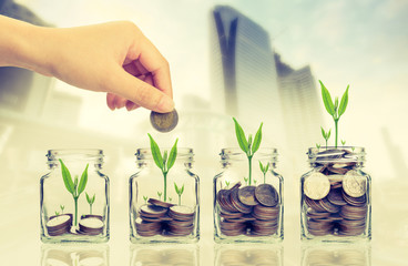 Fototapeta na wymiar Hand putting money coins and seed in clear bottle on cityscape photo blurred cityscape background,Business investment growth concept