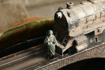 An old and dirty plastic train toy model and miniature plastic military figure model on bridge model scenery represent the train toy for hobby and collection concept related idea.