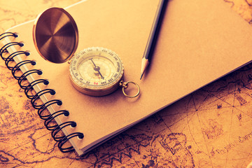 Compass with note book and pencil on old map vintage process style
