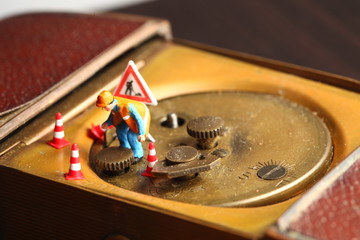 The back side of old and dirty brass table clock and miniature maintenance figure plastic model...