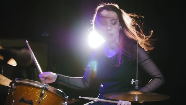 Girl rock musician - female drummer performing, slow-motion