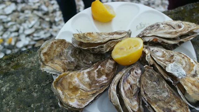 Man opens an oyster and waters it with lemon juice