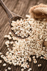 close up of organic millet in wood spoon on wooden rustic table