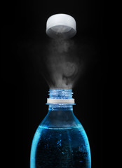 Top of open plastic bottle with carbonated mineral water in the dark
