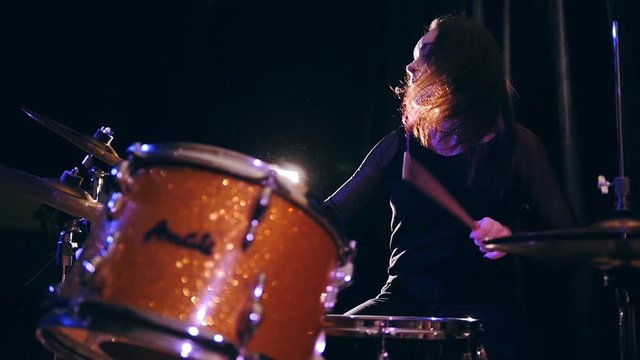 Smiling Dashing teen-girl with flowing hair percussion drummer performing with drums, slow motion