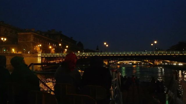 Seine River cruise on boat tour. Tourists on the deck of the ship photographed night Paris