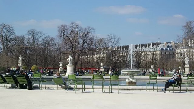 Tourists near the fountain in Les Jardins des Tuileries in Paris, France. Tourists relax and sunbathe in the sun