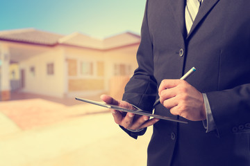Business man working with a digital tablet on blurred home background ,loans concept.vintage process style