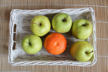Apple and orange in white basket