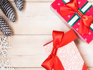 Christmas theme with fir cones along with gift boxes on the wooden background. Top view. Holiday concept