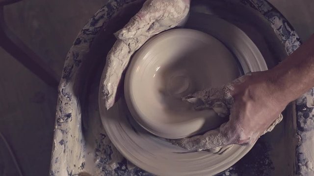 Men's hands are molded on a potter's wheel