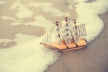 Sailing ship model on the beach, discovery concept in vintage tone style