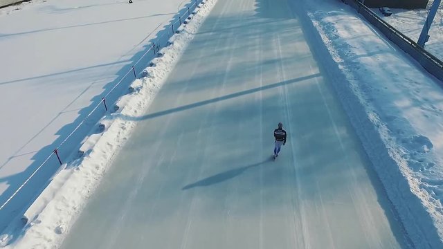 Speed ice skater skating on outdoor race HD aerial video. Flying over professional athlete training for winter olympic