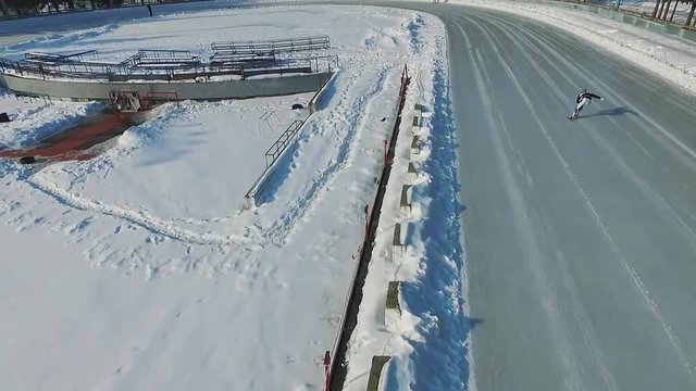 Speed ice skater skating on outdoor race HD aerial video. Flying over professional athlete training for winter olympic