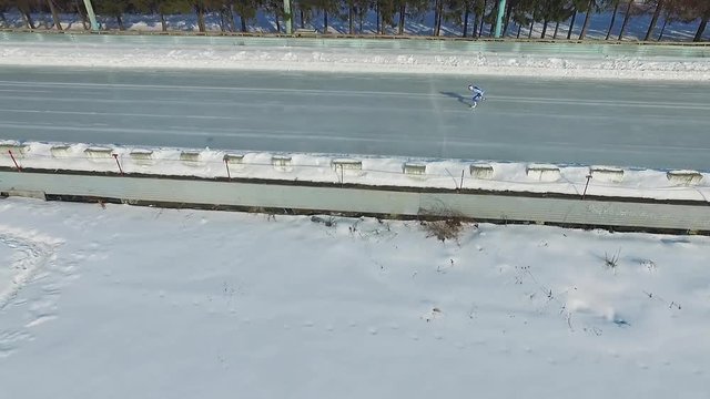 Speed ice skater skating on outdoor race HD aerial video. Flying over professional athlete training for winter olympic side view