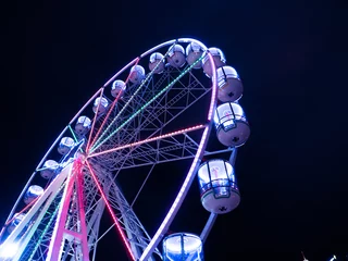 Poster Ferris wheel night illumination in the night dark sky.  White ferris wheel with green color light. © Sanhawat