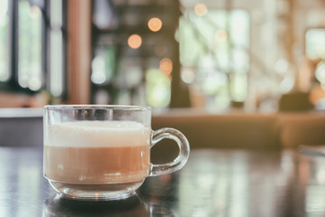Cup of Cappuccino Coffee with foam froth cover on top. Cafe shop bokeh light vintage background.