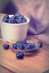 Pot of blueberries with spoon on a rustic background