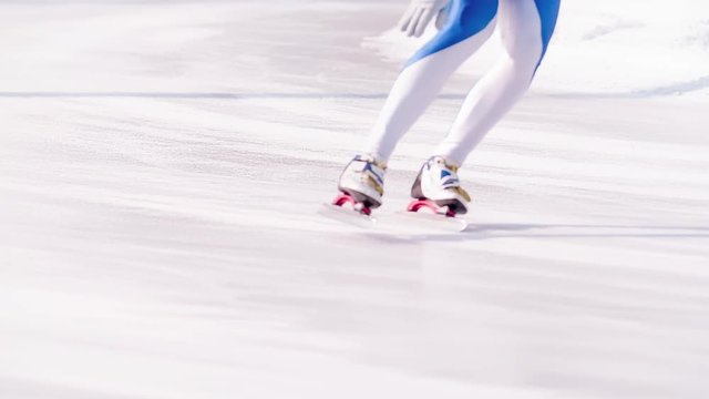 Speed ice skater skating on outdoor race on turn HD slow-motion video. View of professional athlete legs training for winter olympic. Lower body