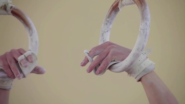 Athlete hand grips gymnastic rings hanging in air close-up slow-motion HD video. Starting training