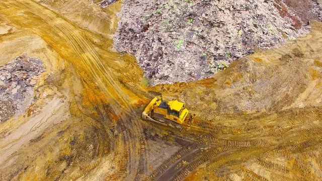 Aerial view of bulldozer on muddy construction site or dump. Heavy industry from above. Industrial background from devastated landscape.