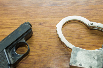 gun and handcuffs on wooden background