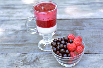 Glass vase full of fragrant red raspberry and blackberry near tasty yogurt with blended berries on...