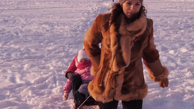 Mom rolls children on a sled in the winter in the city. Full HD