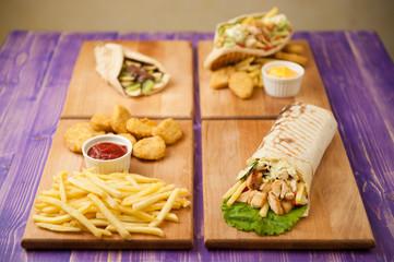 shawarma, nuggets and french fries, Greek gyro and pita with chocolate and kiwi on a table