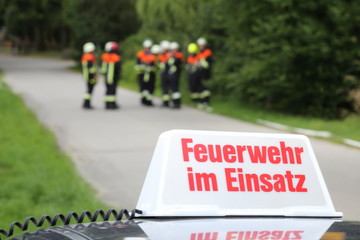 Fototapeta premium Gruppe von Feuerwehrleute hinter Schild Feuerwehr im Einsatz
