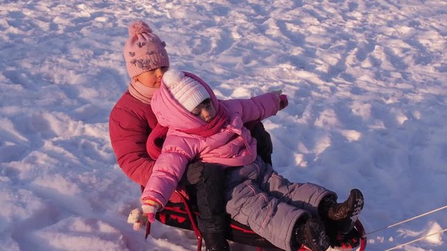 Mom rolls children on a sled in the winter in the city. Full HD