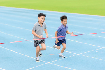 Obraz premium Young Asian boy running on blue track in the stadium