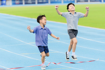 Fototapeta premium Young Asian boy running on blue track in the stadium