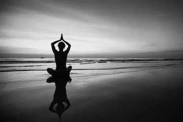 Frau, die Meditation nahe dem Ozeanstrand tut. Schwarz-Weiß-Silhouette. © De Visu