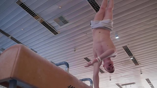 Young gymnast doing routine exercises on pommel horse HD slow-motion video. Olympics athlete training gymnastics skills: handstand