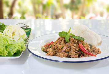 Ground pork salad with sticky rice and fresh vegetable Thai food and Thai called “Larb” on dark wooden table / Selective focus Image

