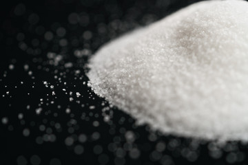 white sugar heap on black background closeup photo, shallow focus