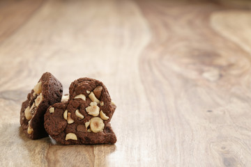homemade heart shaped chocolate cookies with hazelnuts on wood table, shallow focus