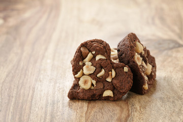 homemade heart shaped chocolate cookies with hazelnuts on wood table, shallow focus