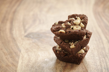 homemade heart shaped chocolate cookies in stack with hazelnuts on wood table, shallow focus