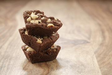homemade heart shaped chocolate cookies in stack with hazelnuts on wood table, shallow focus