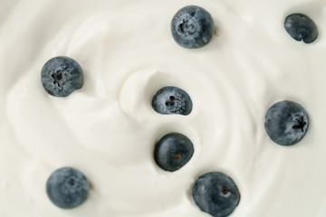macro photo of organic yogurt with fresh blueberries, food background