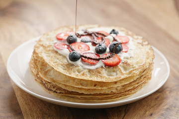 fresh blinis or crepes with fresh berries and cream decorating with chocolate sauce, sweet food