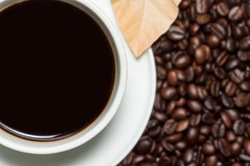 Black coffee in the cup and blur roasted coffee beans background.
