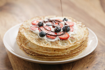 fresh blinis or crepes with fresh berries and cream decorating with chocolate sauce, sweet food